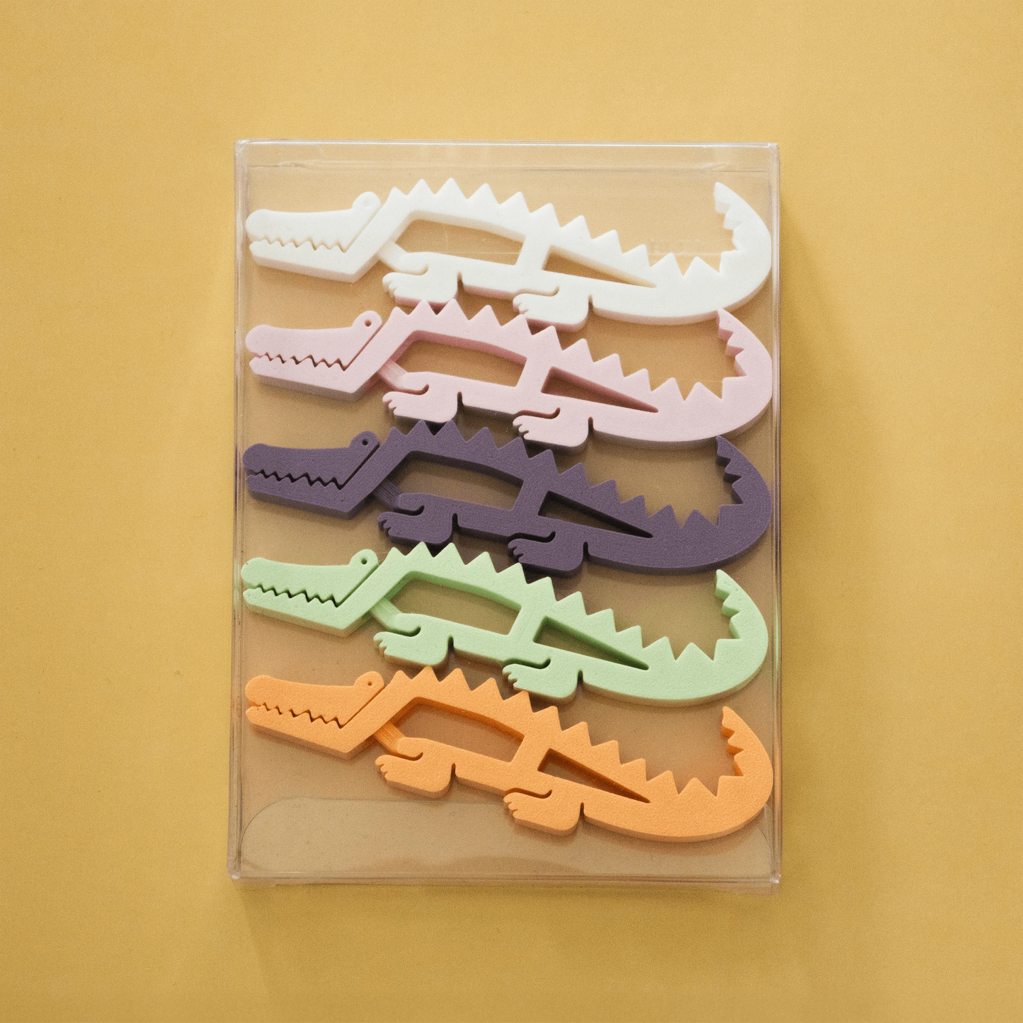Krokoclip clothespin in crocodile design, made of colorful plastic, on a light yellow background.